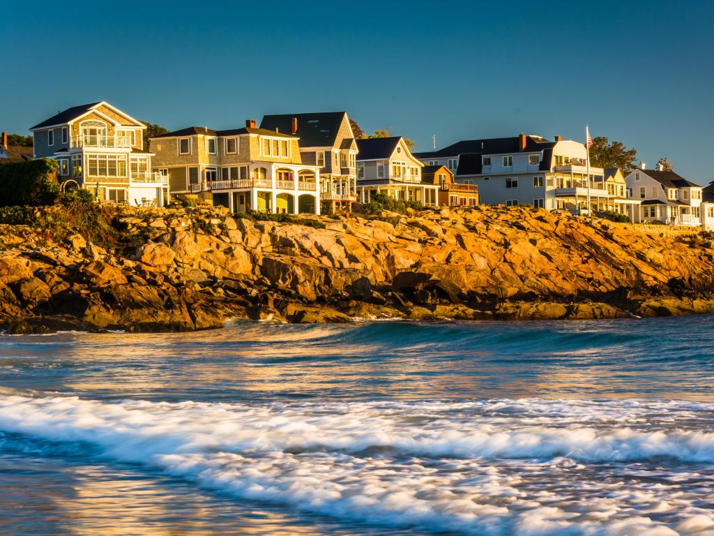 Waves in the Atlantic Ocean and houses on cliffs in York, Maine.