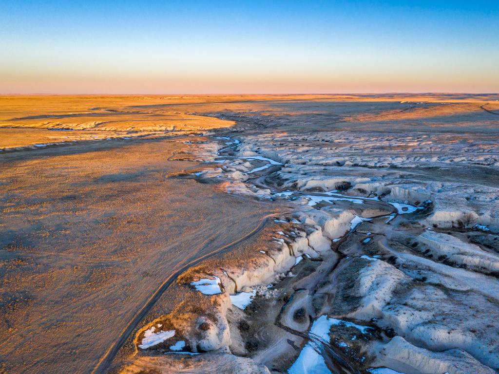 Wide, flat landscape viewed from above with snow-filled canyons