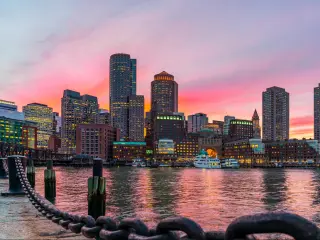 Boston, Massachusetts, USA with the city skyline and Fort Point Channel at sunset as viewed from Fan Pier Park.