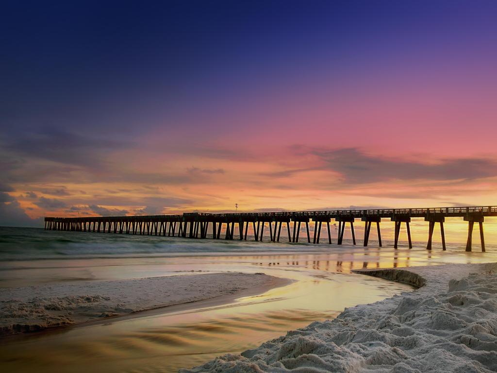 Panama City Beach pier at sunset, with a purple-hued sky and white sandy beach