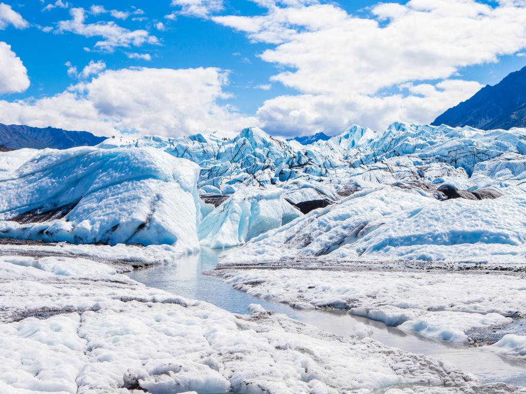 Matanuska Glacier, Alaska taken on a cloudy but sunny day with snow and ice surrounding and mountains in the distance.