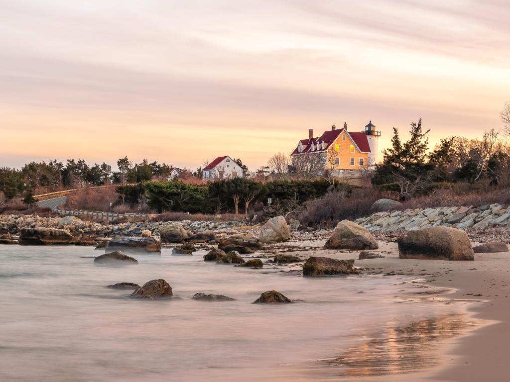 Nobska Lighthouse and rocks by silver water in evening light