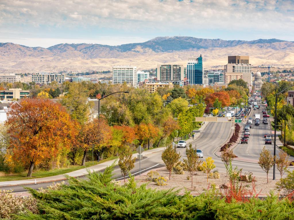 Boise, Idaho, USA with a street leading to the Capital Building in the distance during fall and mountains in the far distance. 