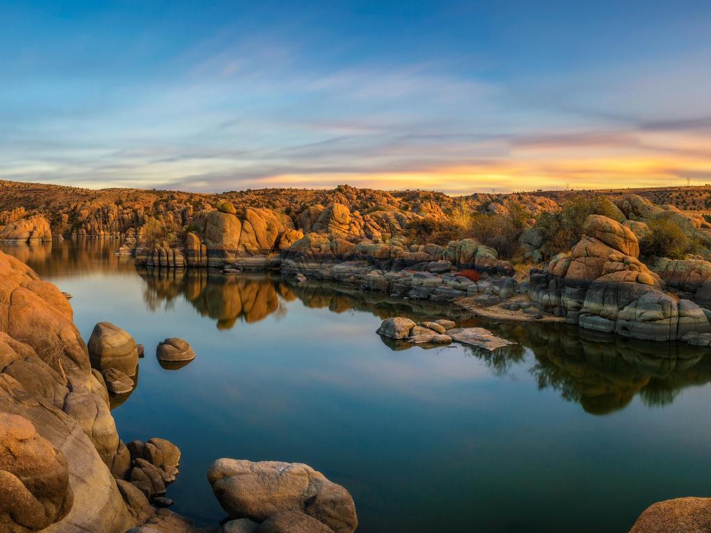 Prescott, Arizona, USA with a sunset above Watson Lake in the foreground and the rocky Granite Dells in the distance.