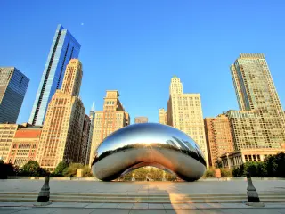 View of the famous metal sculpture in Chicago with tall buildings in the background with blue sky