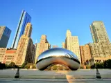 View of the famous metal sculpture in Chicago with tall buildings in the background with blue sky