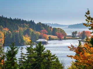 The ocean as seen through fall foliage at Acadia National Park in Maine, with a wooden hut on a jetty 