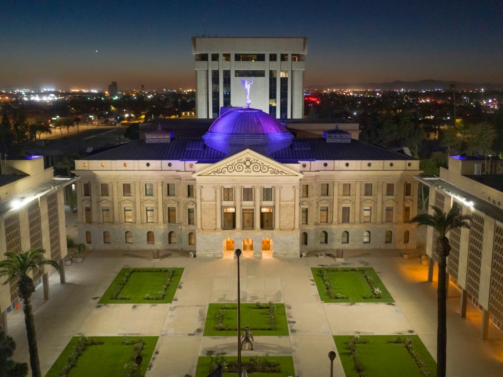 An aerial view of Arizona's Capital building with blue light illuminating its roof and the mesmerizing city lights of Arizona at the back