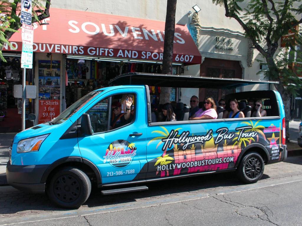 People sitting in an open-top blue van parked in front of a souvernir shop on a sightseeing tour