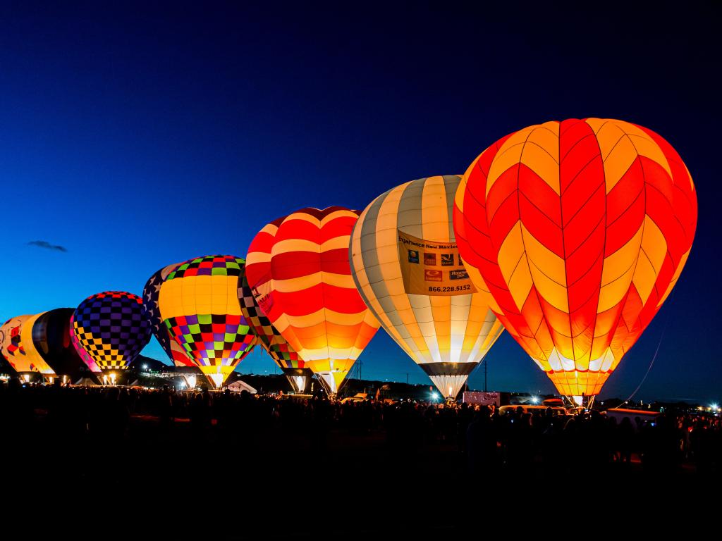 Brightly colour hot air balloons in a very straight line in the dark