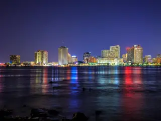 New Orleans, Louisiana, USA with the city downtown in the background and the Mississippi River in the foreground at twilight.