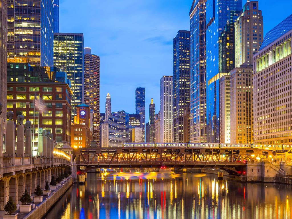 Chicago, Illinois taken at downtown with the Chicago River and tall buildings either side at night and a bridge in the center. 