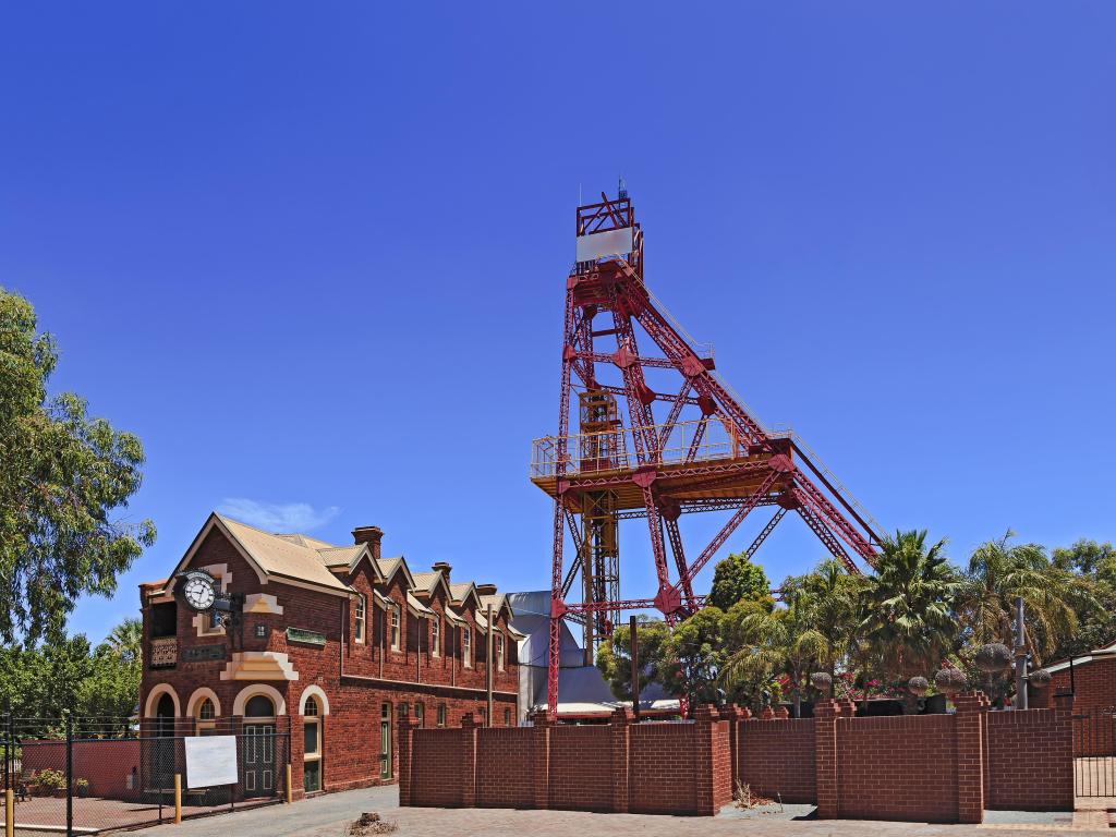 Historic red brick building and industrial mining machinery tower with blue sky and eucalyptus