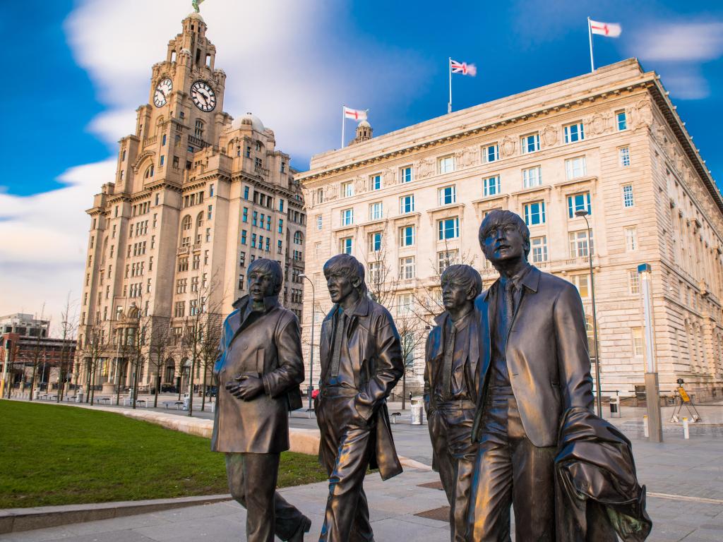 Liverpool, UK taken with the bronze statue of the four Liverpool Beatles stands on Liverpool Waterfront, sculpted by sculpture Andrew Edwards, in the foreground.