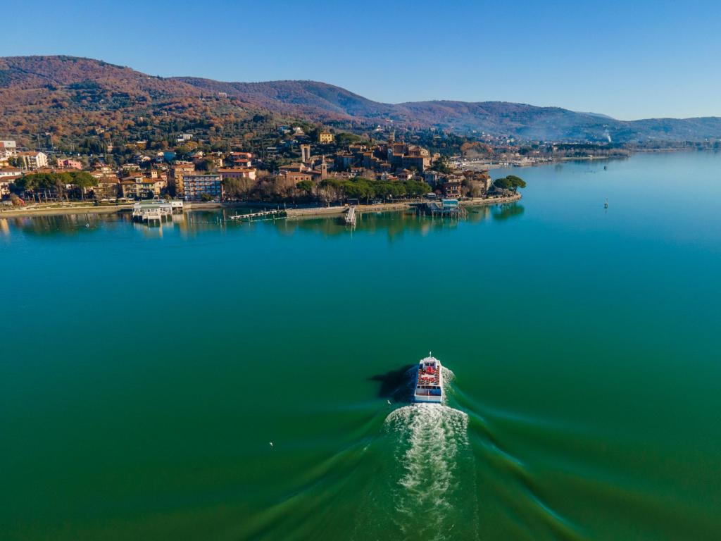 Aerial view of a sailing boat navigating on Passignano sul Trasimeno, a beautiful lake near Perugia, Umbria, Italy.