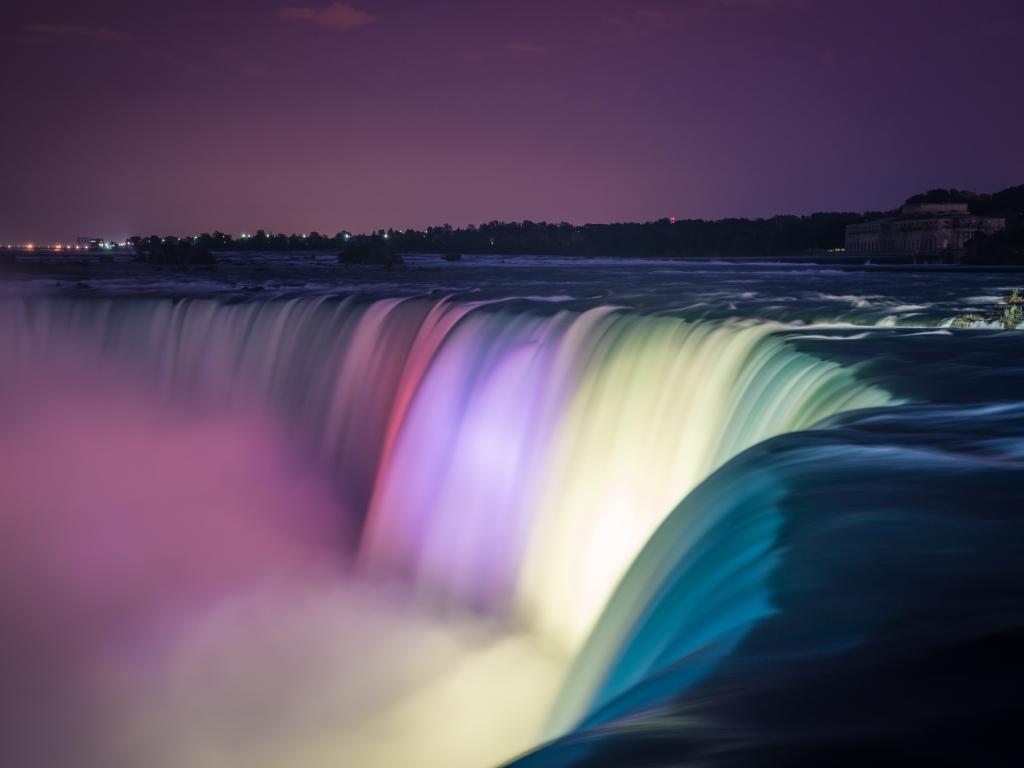 Niagara Falls lit up with multicolored lights at night 