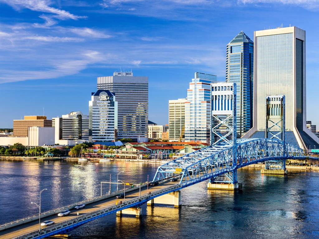 Jacksonville, Florida showing the downtown city skyline in the background and St. Johns River in the foreground with a bridge crossing the two.