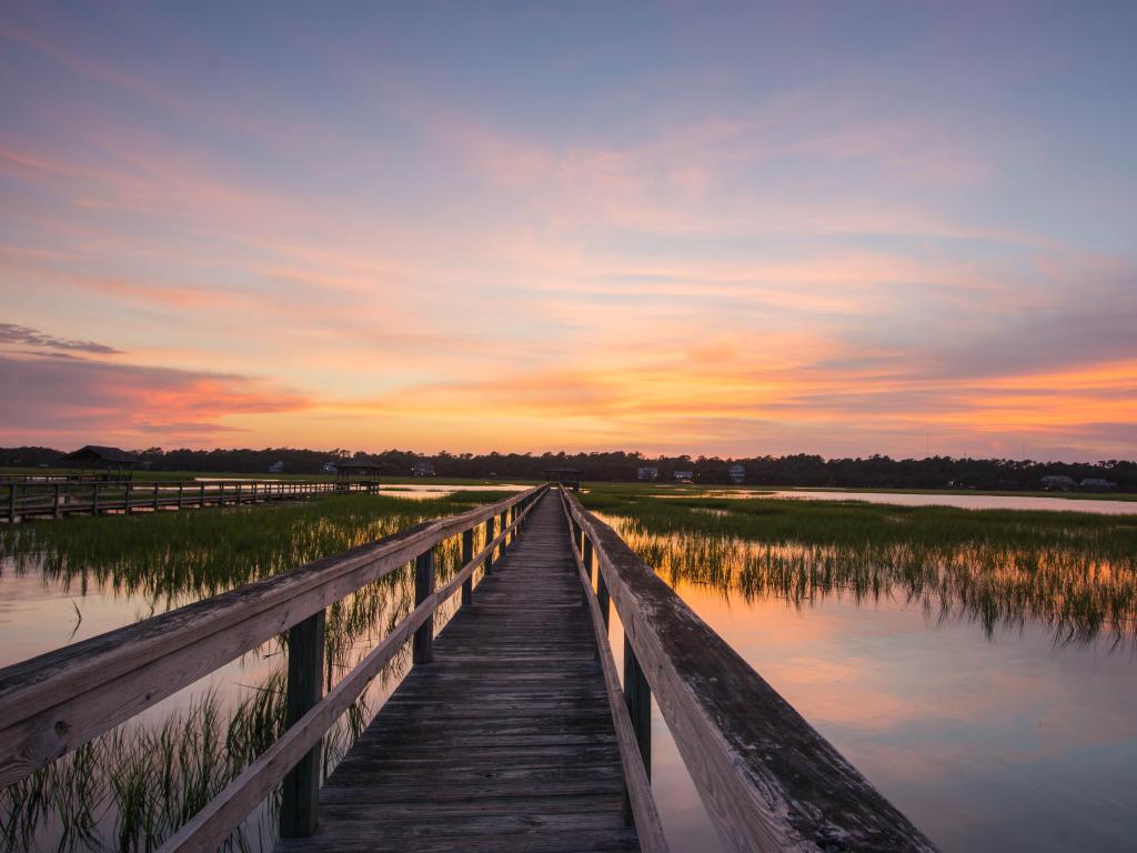 Pawleys Island, South Carolina, USA with a boardwalk and marsh at sunset.