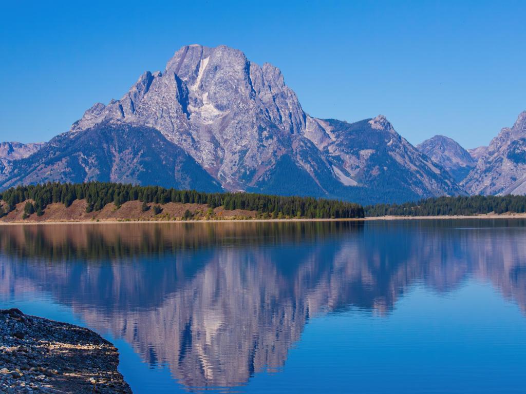 Reflection of the Tetons on calm waters of Jackson Lake on a sunny day