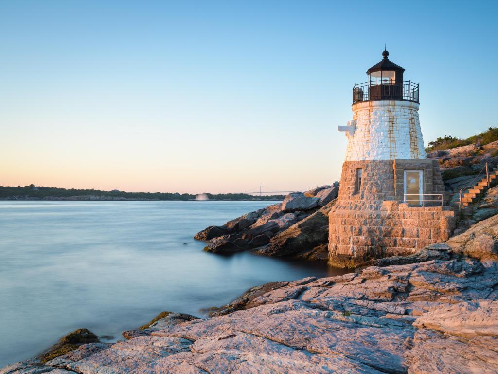 Newport, Rhode Island taken at sunset at Castle Hill Lighthouse with calm water surrounding the base of the lighthouse. 