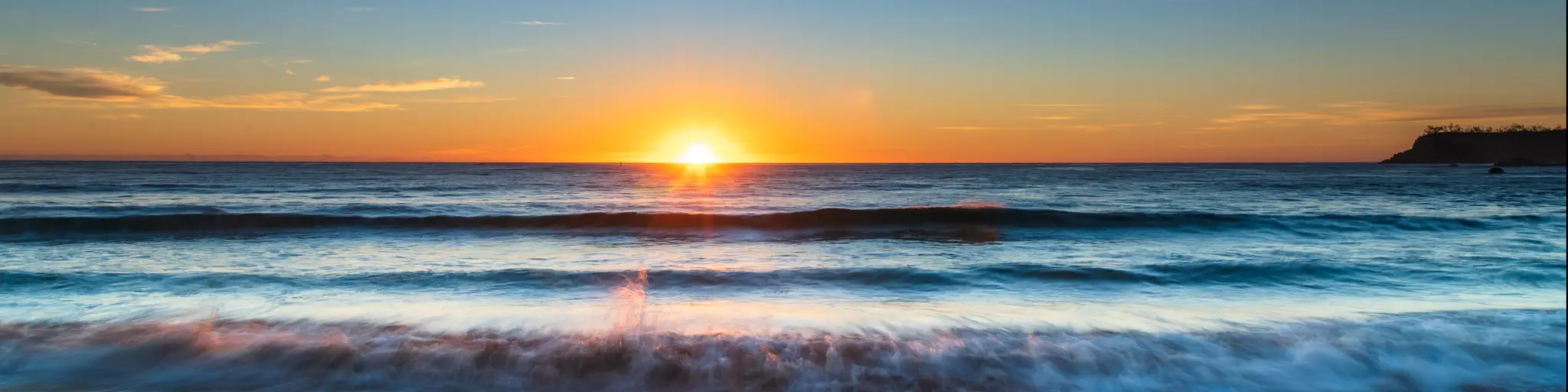 Vibrant sunrise light illuminating calm water breaking on a beach
