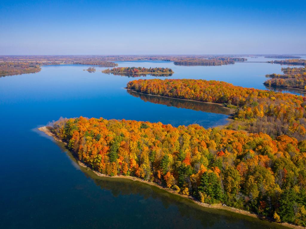 Red, gold and green foliage across heavily wooded banks around lake with many islands