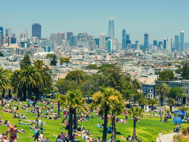 People relaxing in Mission Dolores Park with amazing views of San Francisco.