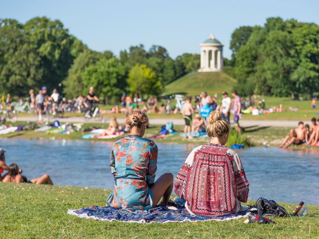 People enjoying the summer, sunbathing, swimming in river Izar and relaxing on green of the Englischer Garten in Munich