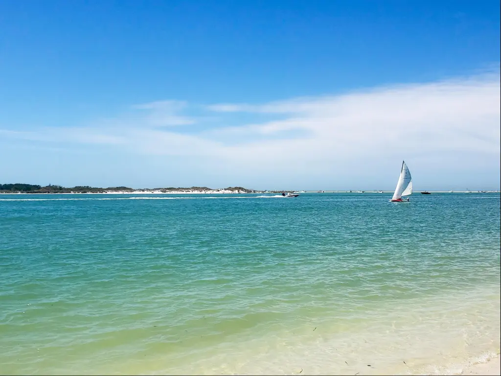 A single sailboat on the turquoise waters surrounding Shell Island in Florida