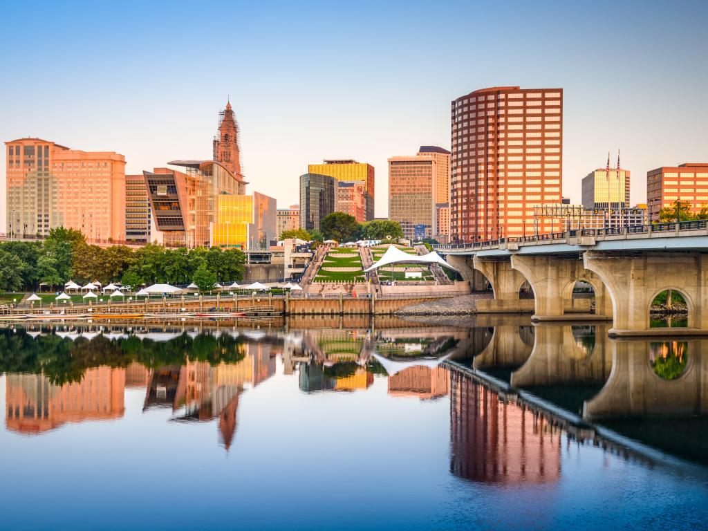 Skyline reflected into calm river water with bridge