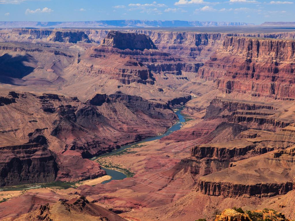 Expansive view of the red rock formations of the canyon, with the Colorado River running through