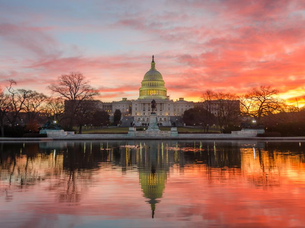 Capitol Building in a cloudy sunrise with mirror reflection in pool in the foreground