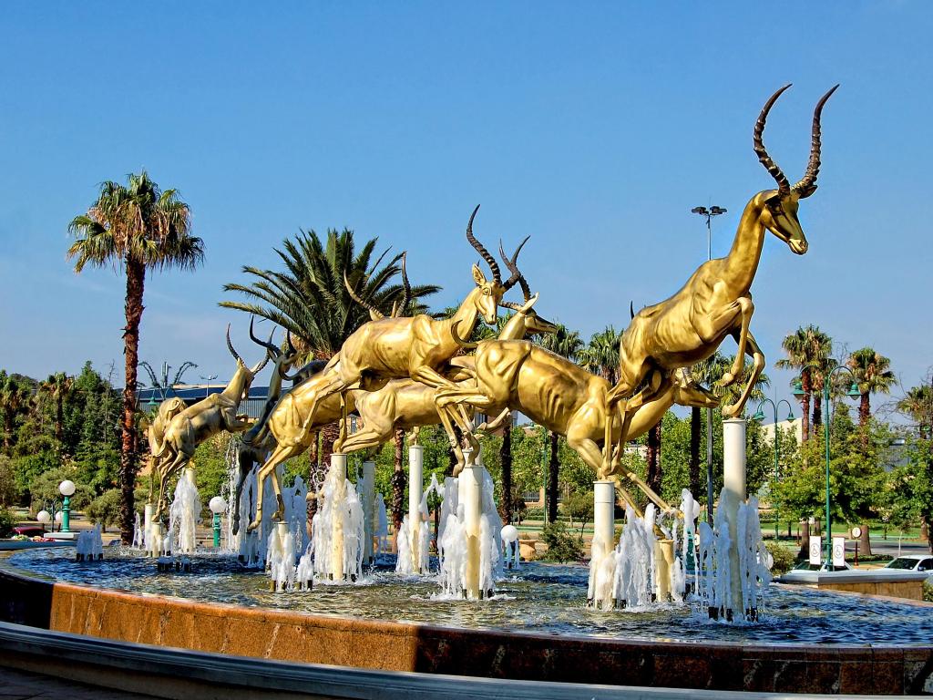 A beautiful fountain with golden springboks jumping over the water, photo taken on a sunny day