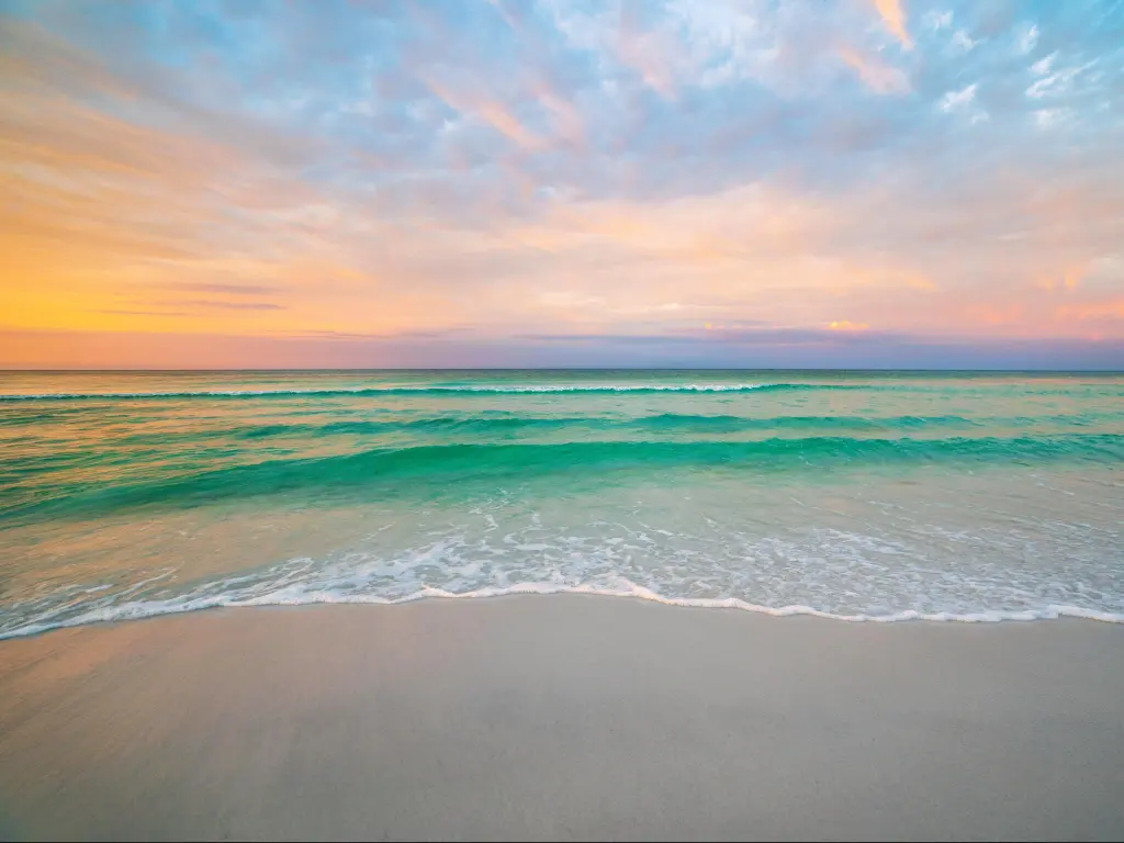 Destin, Florida, USA during morning sunrise with calm water and soft sand in the foreground.