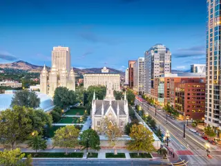 Downtown cityscape of Temple Square surrounded with buildings and mountains in the distance, taken at dusk