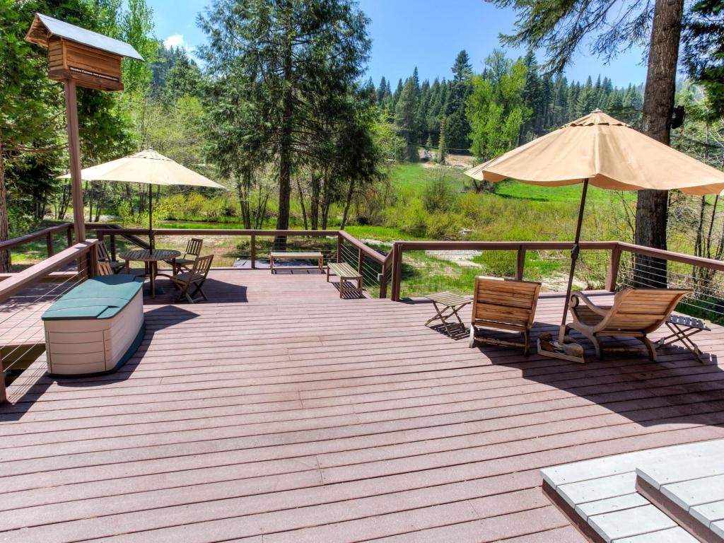 Relaxing deck overlooking stunning meadow of Big Creek, with bright blue skies and lush forest