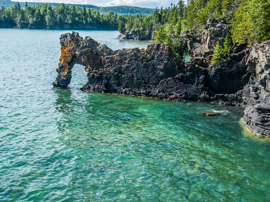 Thunder Bay, Ontario with a rock formation called the Sea Lion, in the foreground and surrounded by Lake Superior, with trees in the distance on a sunny day.
