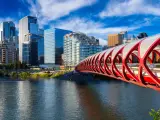 Peace Bridge across Bow River with Calgary city buildings in the background during a vibrant summer sunrise