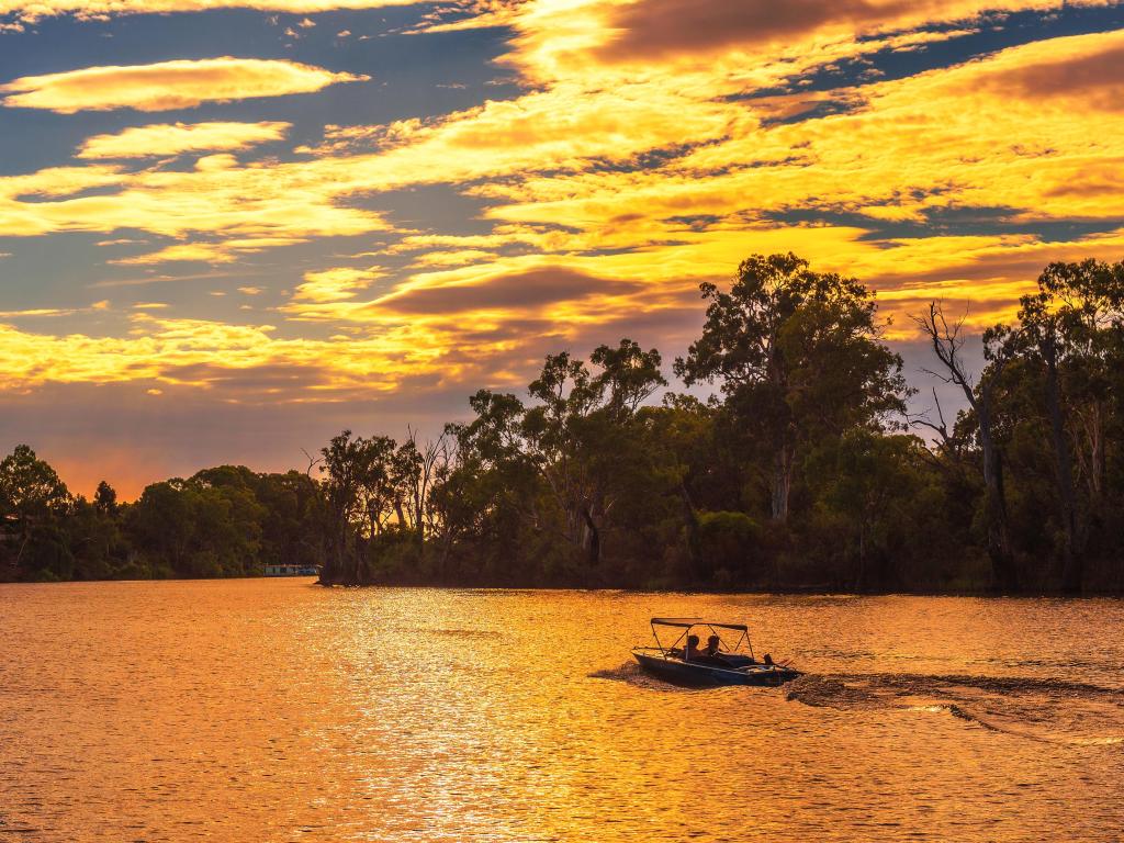 Mildura, Australia taken at sunset over Murray river with people riding a boat.
