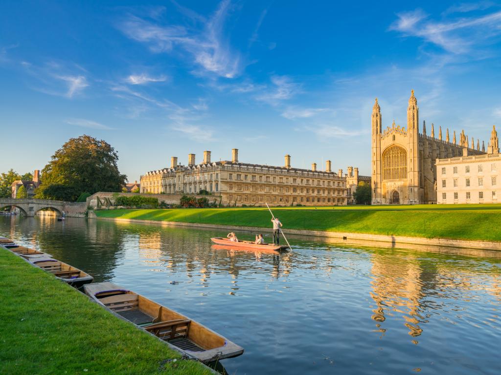 Cambridge, UK with a beautiful view of college in Cambridge with people punting on river cam on a sunny day.