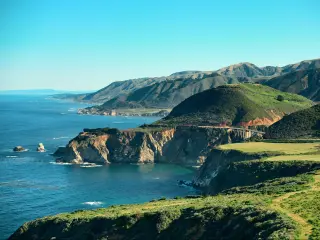 Big Sur, California, USA with a seascape view of the iconic Big Sur road alongside cliffs and the sea on a sunny day.