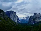 A breathtaking view of Rock formations, waterfall, and pine trees in Yosemite National Park on a gloomy afternoon