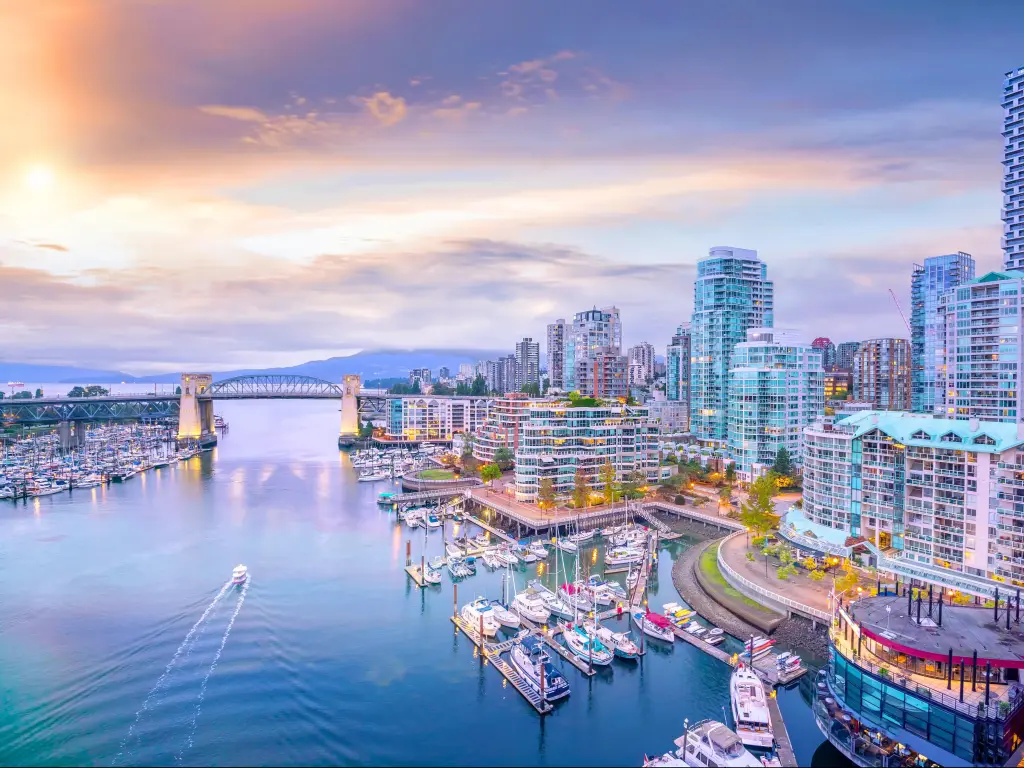 Vancouver skyline, British Columbia, Canada at sunset with boats in the harbor and mountains in the far distance. 