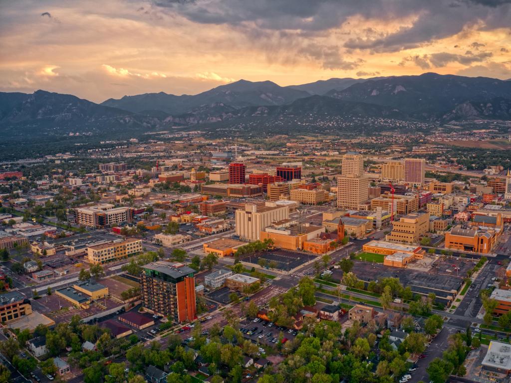 Colorado Springs, Colorado, USA with an aerial view of Colorado Springs at dusk with the mountains in the distance.