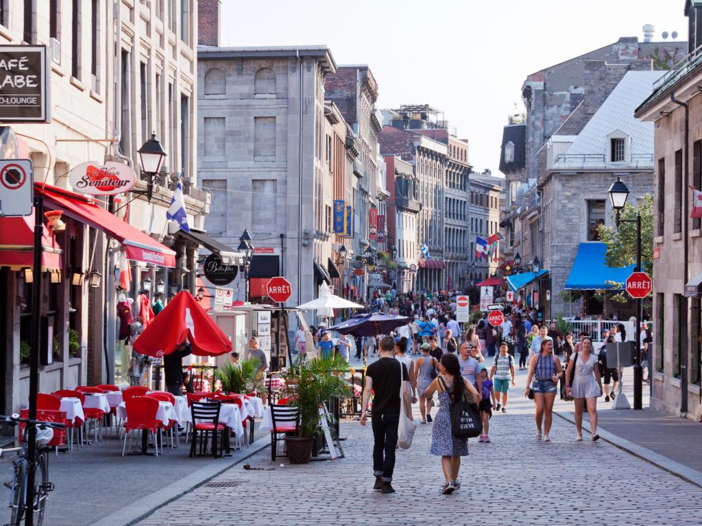 People walk in the cobbled streets outside restaurants in Old Town Montreal in the summertime