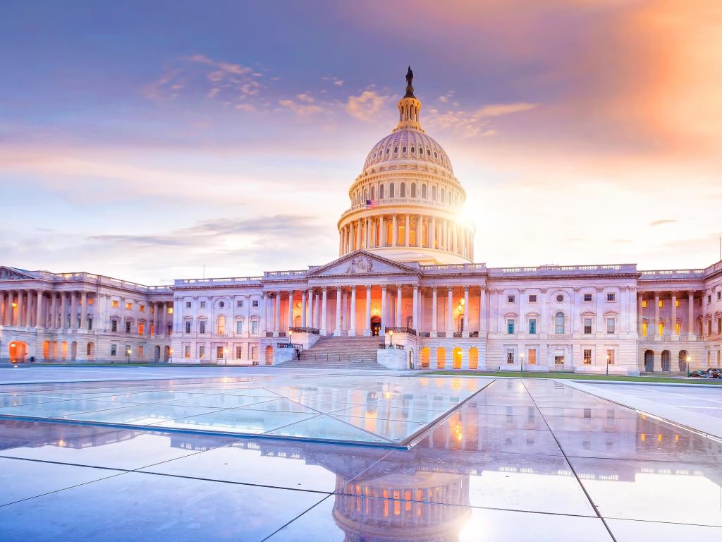 The United States Capitol building with the dome lit up at sunset