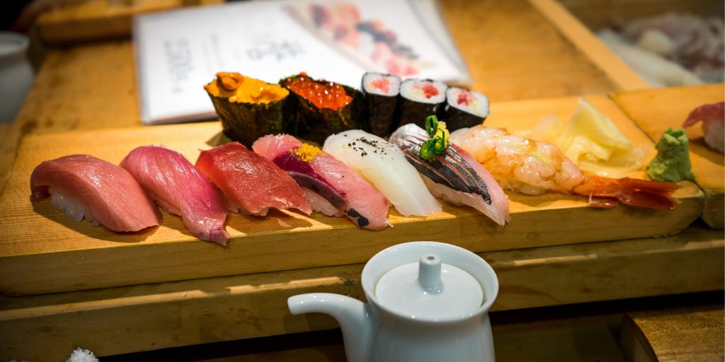 A wooden plank with a row of colourful sushi 