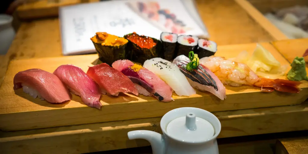 A wooden plank with a row of colourful sushi 