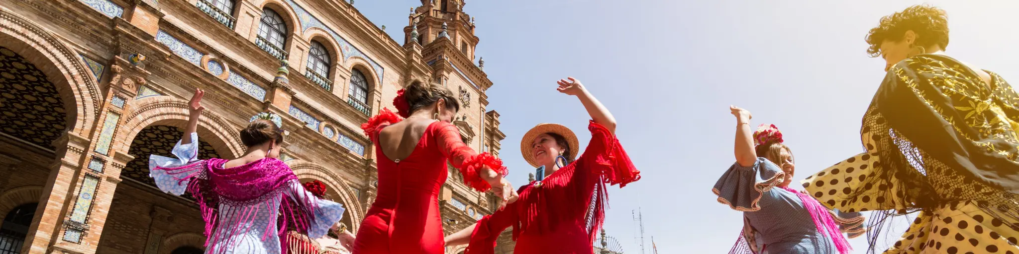 Flamenco dancers in Plaza España, Spain, two wearing red, the others in blue and pink dresses