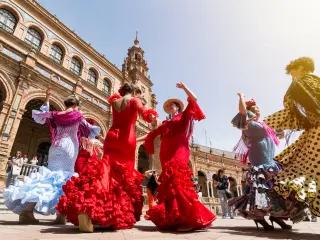 Flamenco dancers in Plaza España, Spain, two wearing red, the others in blue and pink dresses